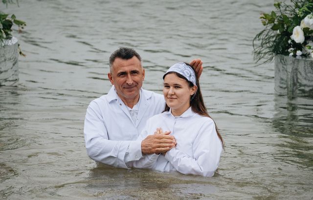 Служитель складає руки дівчини на грудях перед зануренням