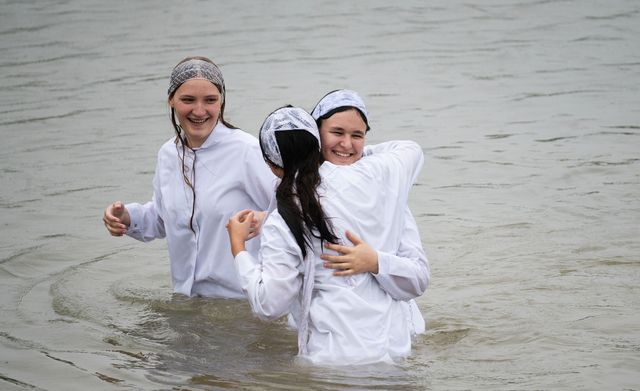 Дві сестри обіймаються у воді після хрещення
