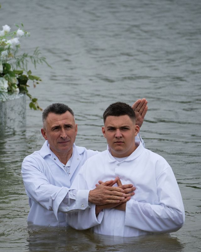 Служитель благословляє юнака у воді