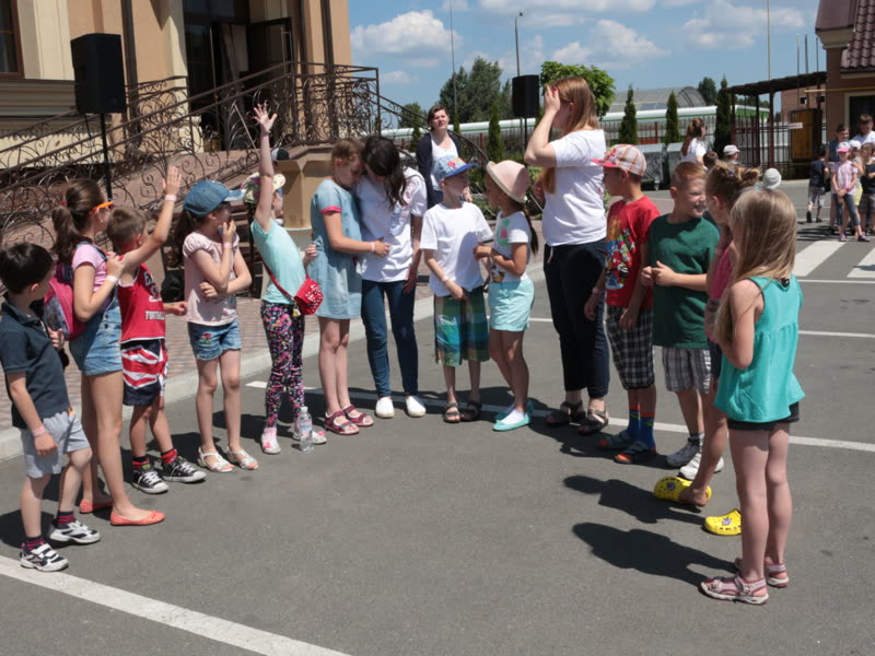 Діти піднімають руки під час гри на майданчику біля церкви