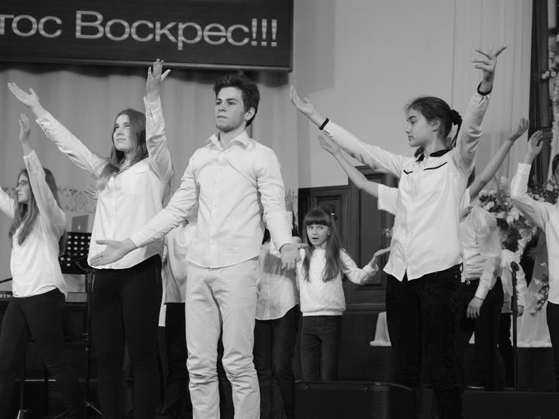 Підлітки з піднятими руками на великодній програмі, чорно-біле фото